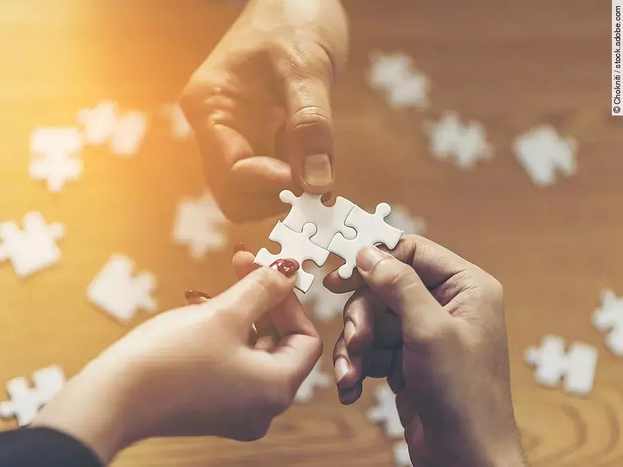 Drei Hände setzen drei Puzzlestücke zusammen