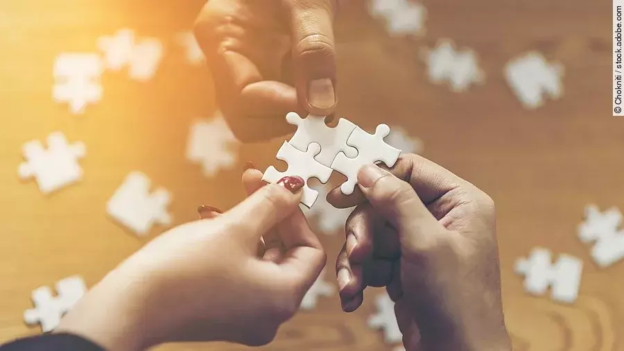 Drei Hände setzen drei Puzzlestücke zusammen