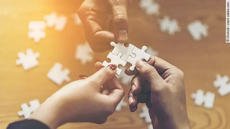 Zusammenschluss Drei Hände setzen drei Puzzlestücke zusammen