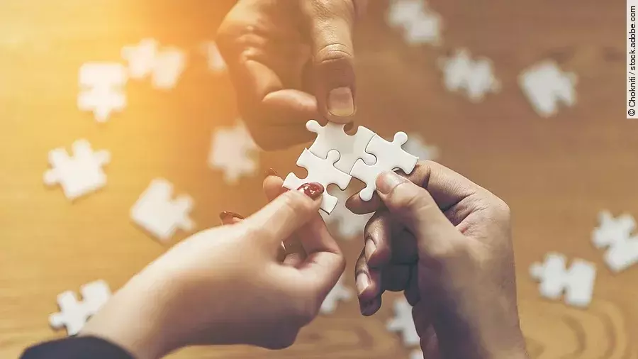 Zusammenschluss Drei Hände setzen drei Puzzlestücke zusammen