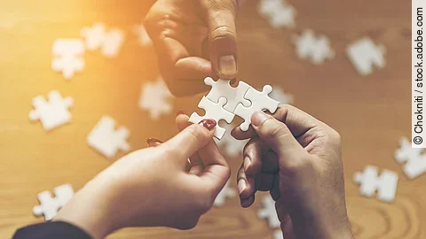 Drei Hände setzen drei Puzzlestücke zusammen