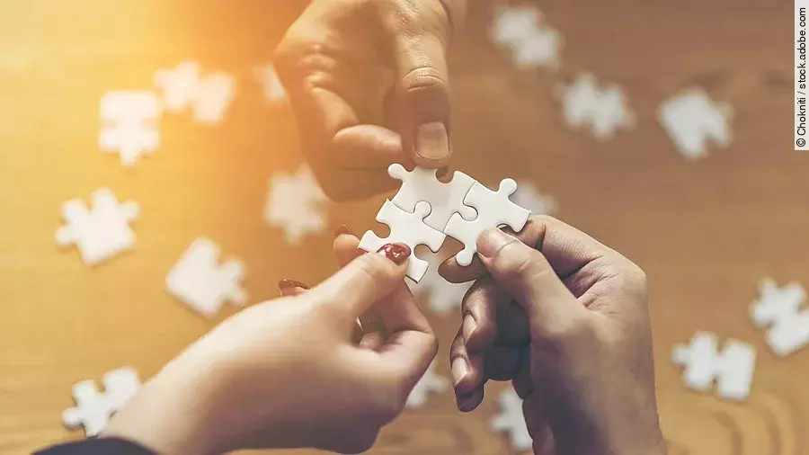 Drei Hände setzen drei Puzzlestücke zusammen