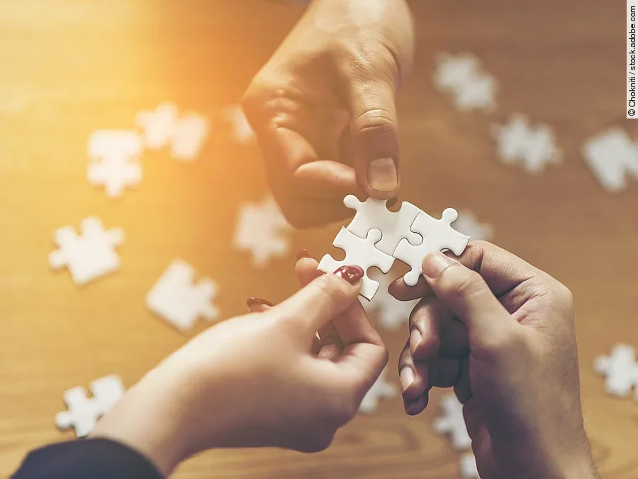 Drei Hände setzen drei Puzzlestücke zusammen