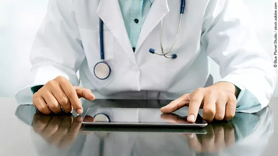 Arzt sitzt an einem Tisch und vor ihm liegt ein Tablet,