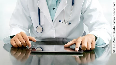 Arzt mit Tablet Arzt sitzt an einem Tisch und vor ihm liegt ein Tablet,