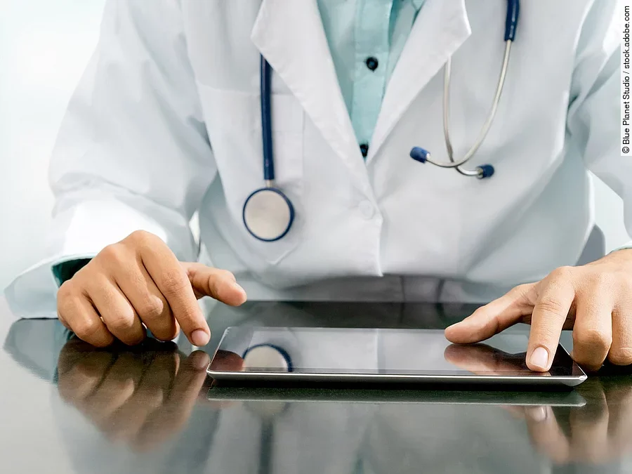 Arzt mit Tablet Arzt sitzt an einem Tisch und vor ihm liegt ein Tablet,