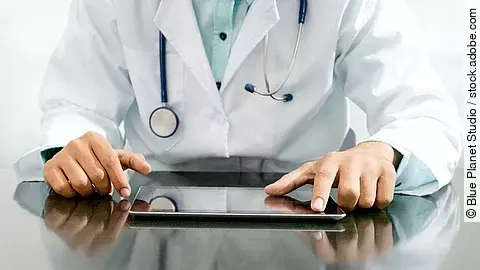 Arzt mit Tablet Arzt sitzt an einem Tisch und vor ihm liegt ein Tablet,