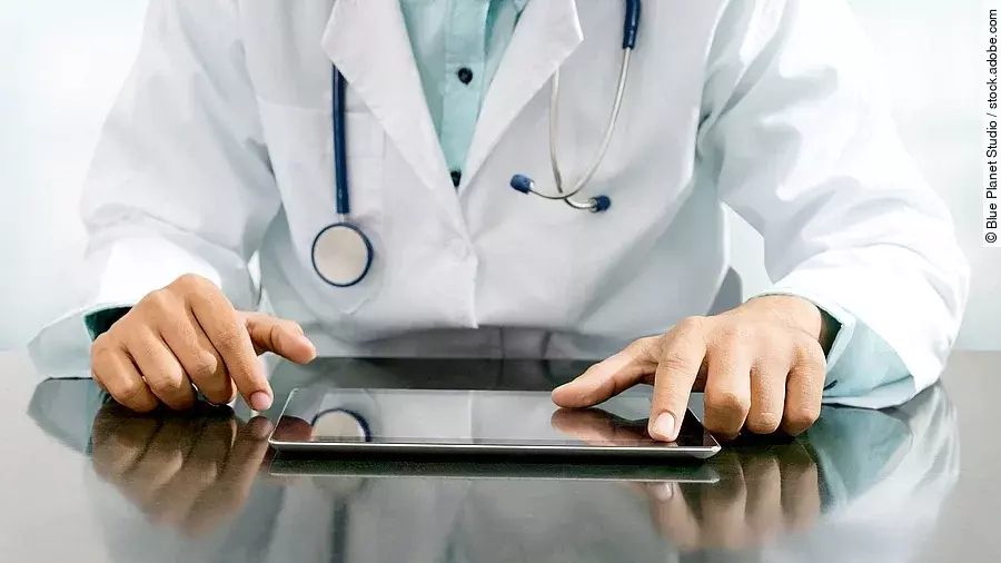 Arzt sitzt an einem Tisch und vor ihm liegt ein Tablet,