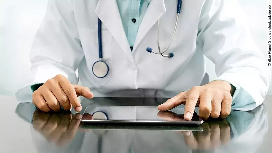 Arzt sitzt an einem Tisch und vor ihm liegt ein Tablet,