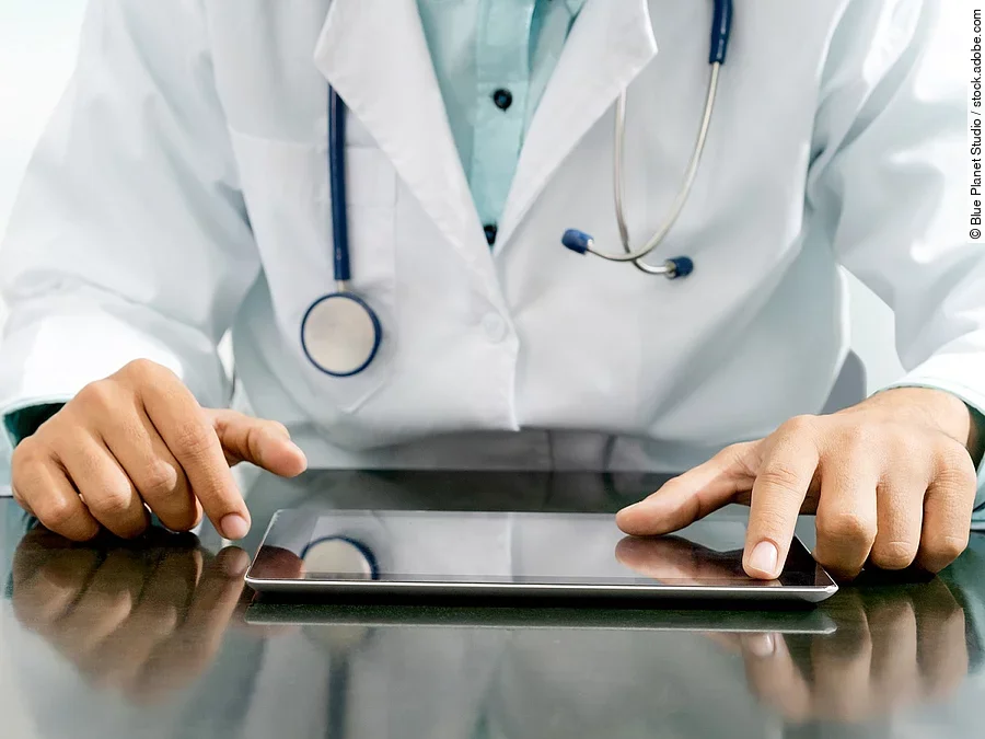 Arzt sitzt an einem Tisch und vor ihm liegt ein Tablet,