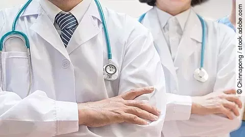 Klinikpersonal Drei Personen stehen nebeneinander. Links ein Arzt in weißem Kittel, in der Mitte eine Ärztin mit weißem Kittel, rechts eine Krankenschwester in blauem Kasack. Es sind jeweils nur die Torsi zu sehen. Alle drei haben ein Stethoskop.