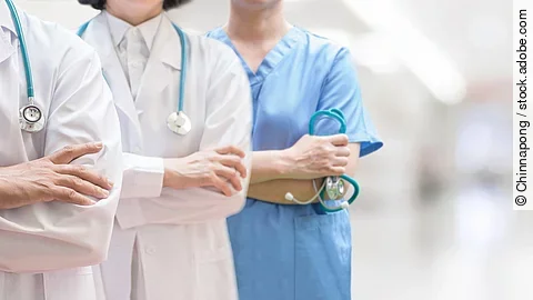 Klinikpersonal Drei Personen stehen nebeneinander. Links ein Arzt in weißem Kittel, in der Mitte eine Ärztin mit weißem Kittel, rechts eine Krankenschwester in blauem Kasack. Es sind jeweils nur die Torsi zu sehen. Alle drei haben ein Stethoskop.