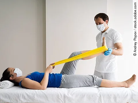 Patientin auf einer Liege wird von Physiotherapeut behandelt