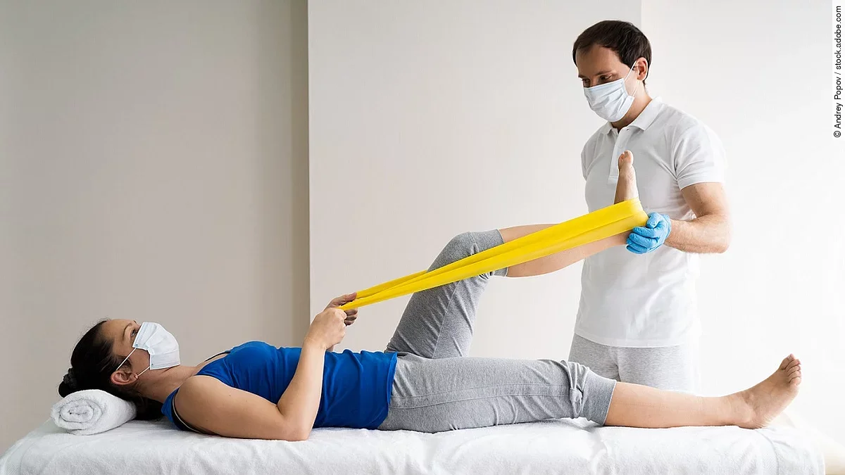 Physiotherapie Patientin auf einer Liege wird von Physiotherapeut behandelt