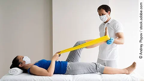 Physiotherapie Patientin auf einer Liege wird von Physiotherapeut behandelt