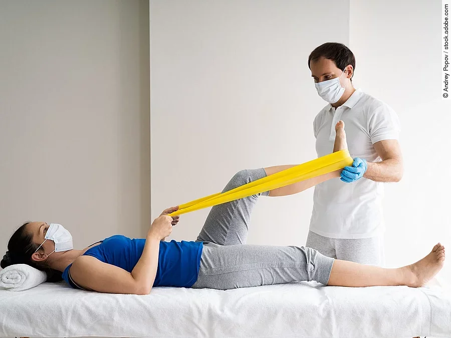 Physiotherapie Patientin auf einer Liege wird von Physiotherapeut behandelt