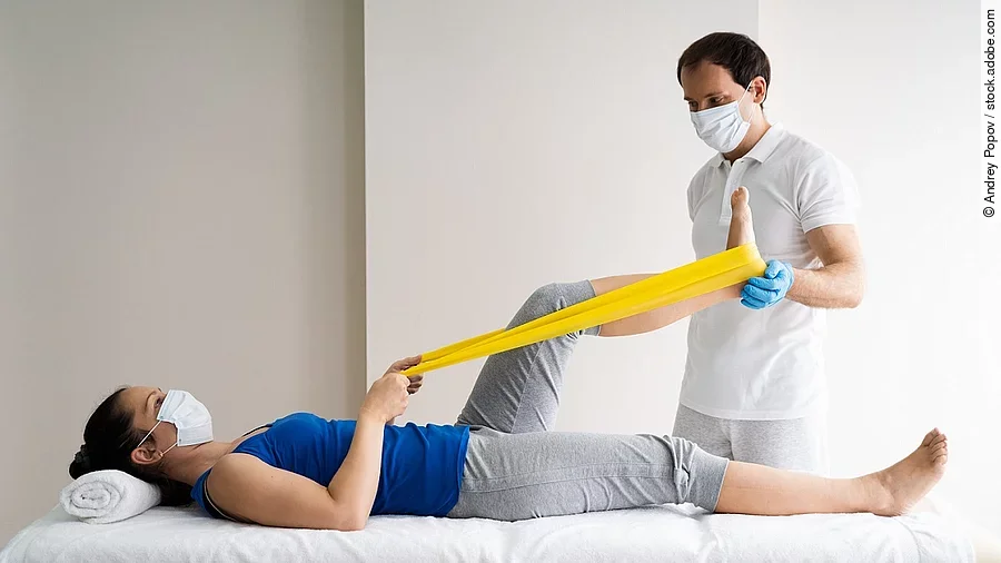 Physiotherapie Patientin auf einer Liege wird von Physiotherapeut behandelt