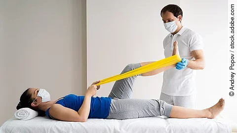 Patientin auf einer Liege wird von Physiotherapeut behandelt