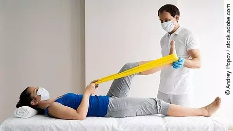 Patientin auf einer Liege wird von Physiotherapeut behandelt