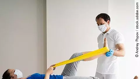 Physiotherapie Patientin auf einer Liege wird von Physiotherapeut behandelt