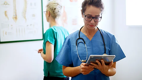 Pflegefachkraft schaut auf das Tablet in ihrer Hand.