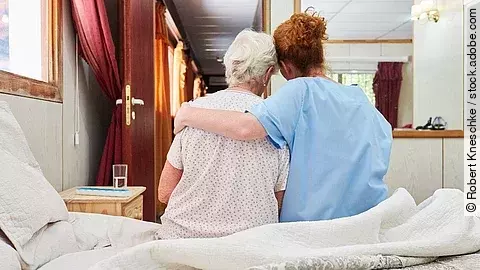 Krankenpflegerin umarmt Seniorin