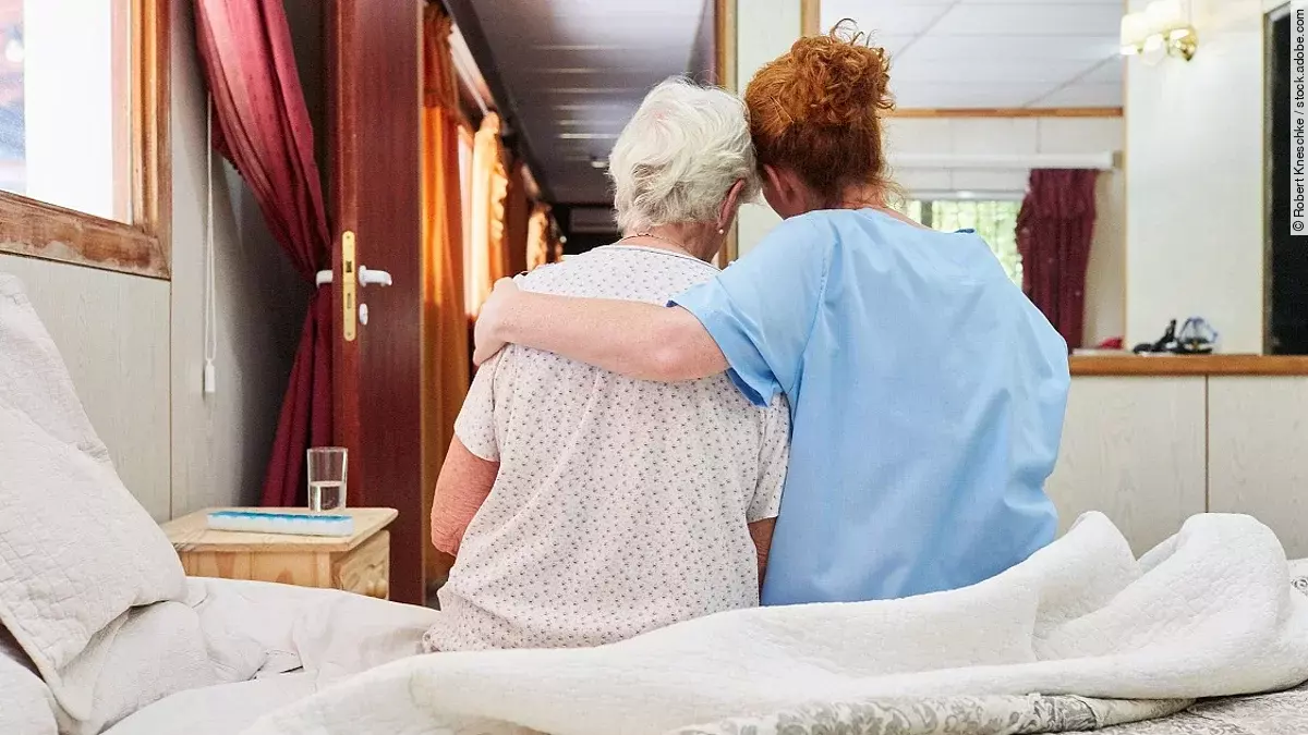 Krankenpflegerin umarmt Seniorin