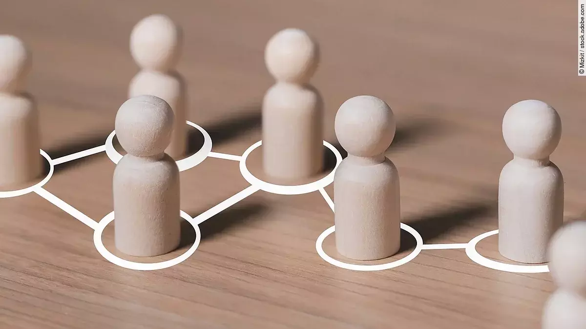 Weiße mit Linien verbundene Kreise, in denen hölzerne Spielfiguren stehen