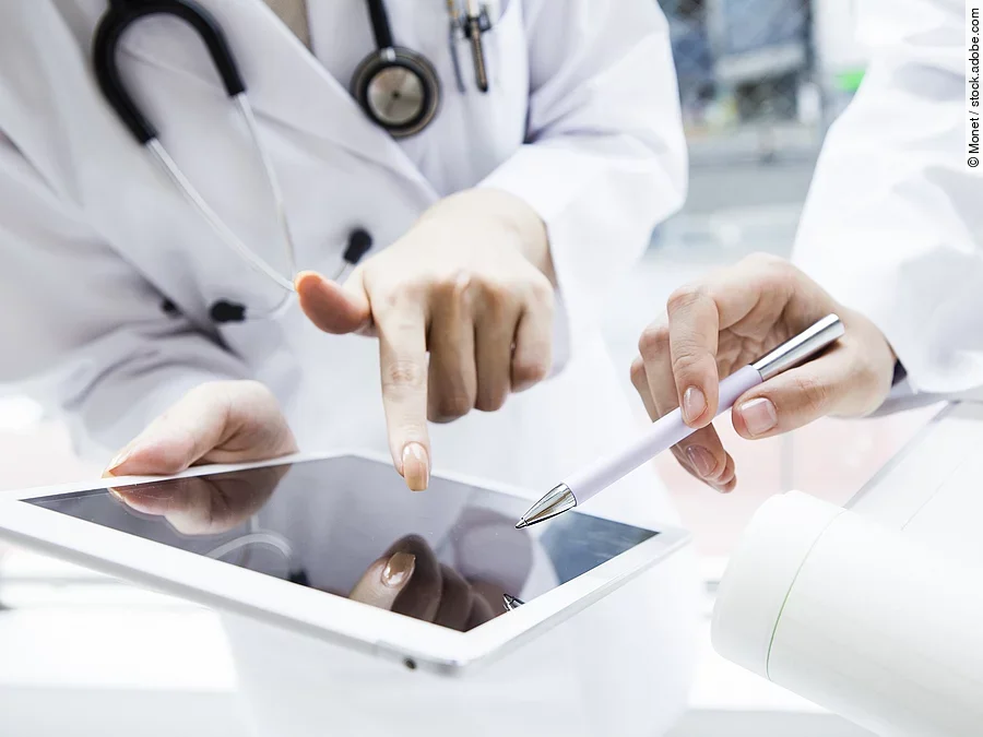 Zwei Ärzte in weißen Kitteln bearbeiten etwas auf einem Tablet.