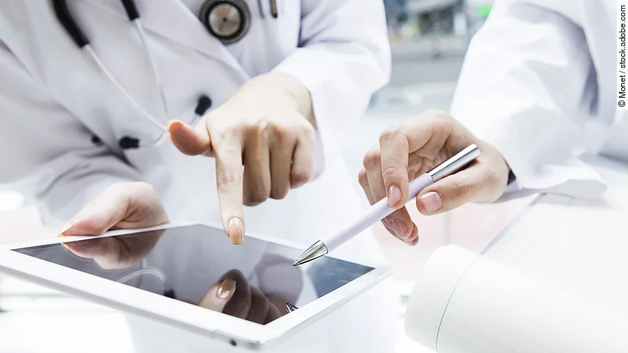 E-Health Zwei Ärzte in weißen Kitteln bearbeiten etwas auf einem Tablet.