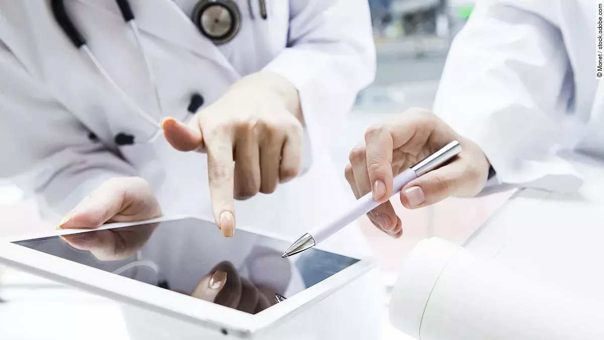 E-Health Zwei Ärzte in weißen Kitteln bearbeiten etwas auf einem Tablet.