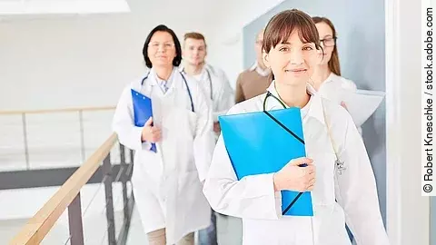 Ärztinnen Drei Ärztinnen mit blauen Mappen unterm Arm im Krankenhausflur unterwegs