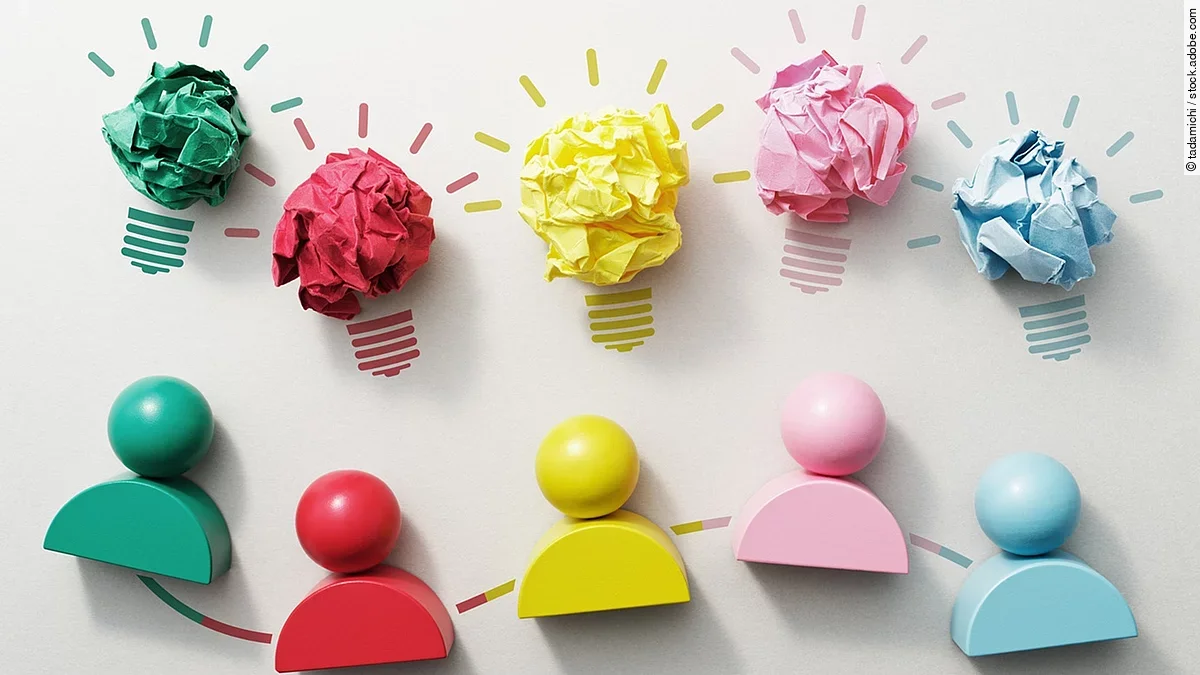 Kommunikation Fünf verschiedenfarbige Holzfiguren nebeneinender, darüber Glühbirnen aus Papier