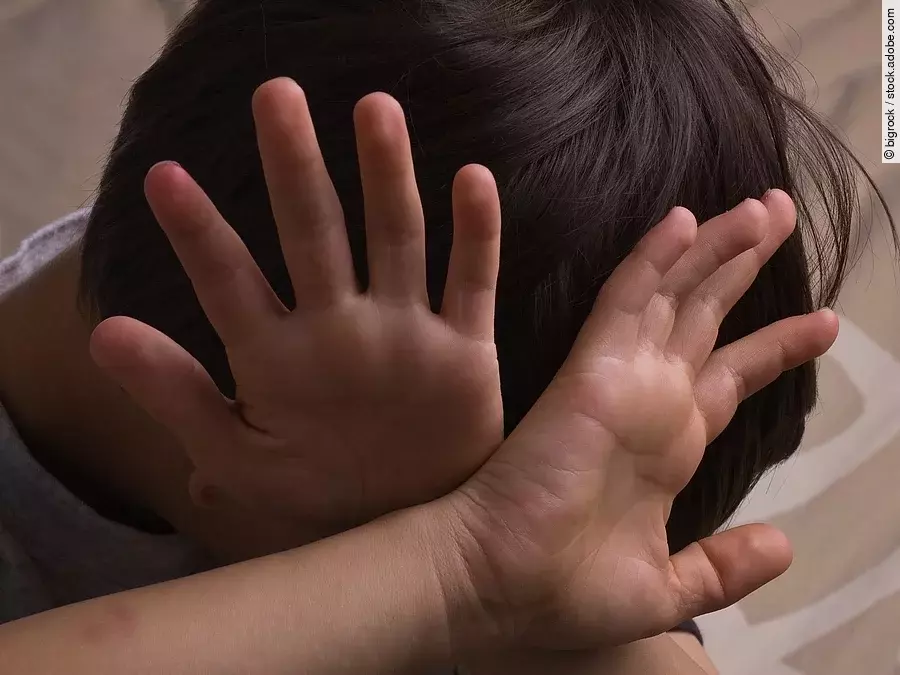 Ein Kind hält sich abwehrend die Hände vors Gesicht.