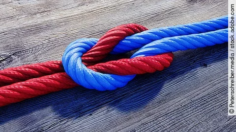 Ein rotes und ein blaues Seil bilden einen Kreuzknoten.