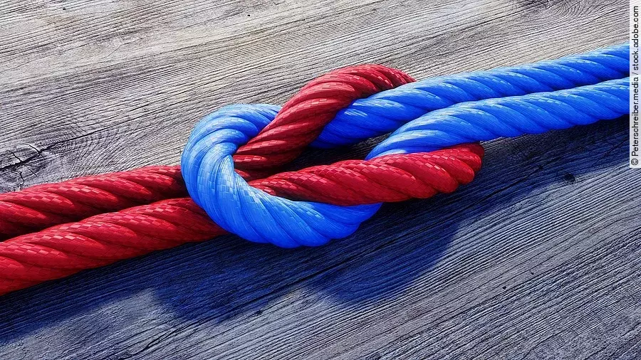 Ein rotes und ein blaues Seil bilden einen Kreuzknoten.