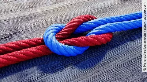 Ein rotes und ein blaues Seil bilden einen Kreuzknoten.