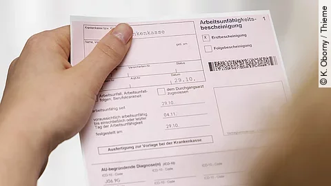 Eine Person hält eine Arbeitsunfähigkeitsbescheinigung in der Hand.