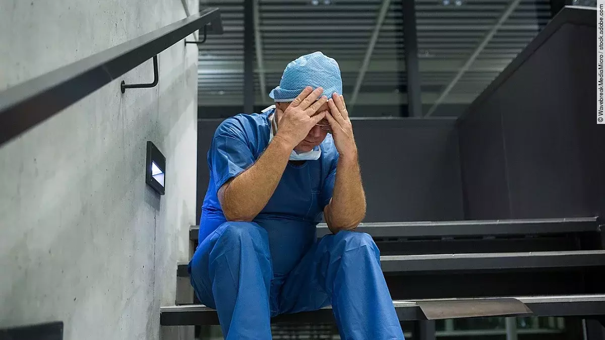 Ein Arzt sitzt nach einer OP verzweifelt auf einer Treppe.