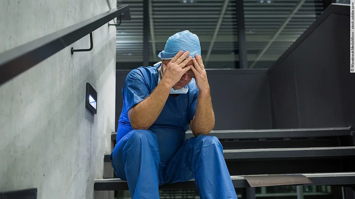 Ein Arzt sitzt nach einer OP verzweifelt auf einer Treppe.