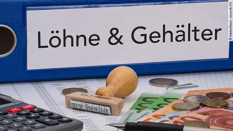 Gehalt Ein dicker Ordner, auf dem "Löhne & Gehälter" steht. Davor liegen ein Taschenrechner, einige Geldscheine, ein Stempel und ein Kugelschreiber.