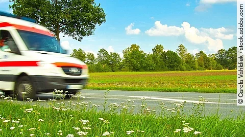 Ein Krankenwagen fährt schnell über eine Landstraße.