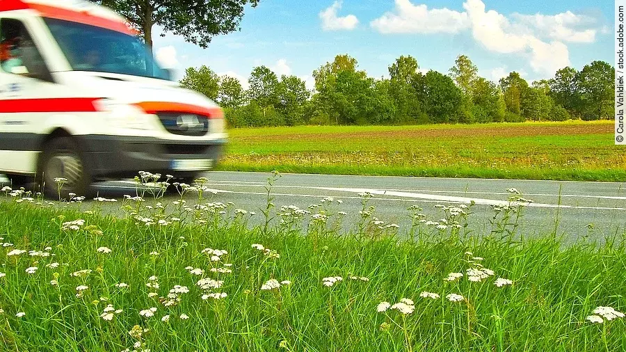 Ein Krankenwagen fährt schnell über eine Landstraße.