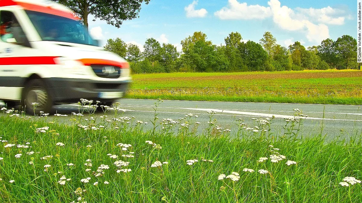 Ein Krankenwagen fährt schnell über eine Landstraße.