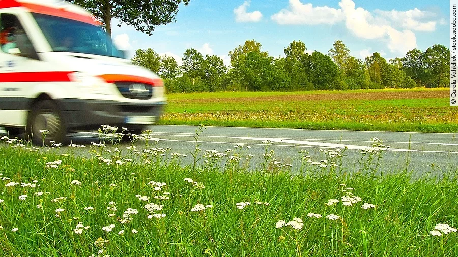 Ein Krankenwagen fährt schnell über eine Landstraße.