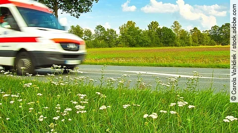 Ein Krankenwagen fährt schnell über eine Landstraße.