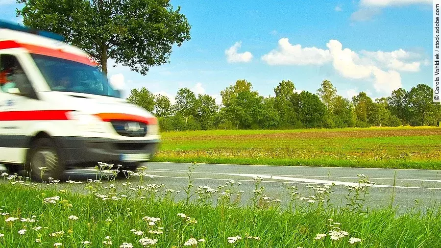 Ein Krankenwagen fährt schnell über eine Landstraße.