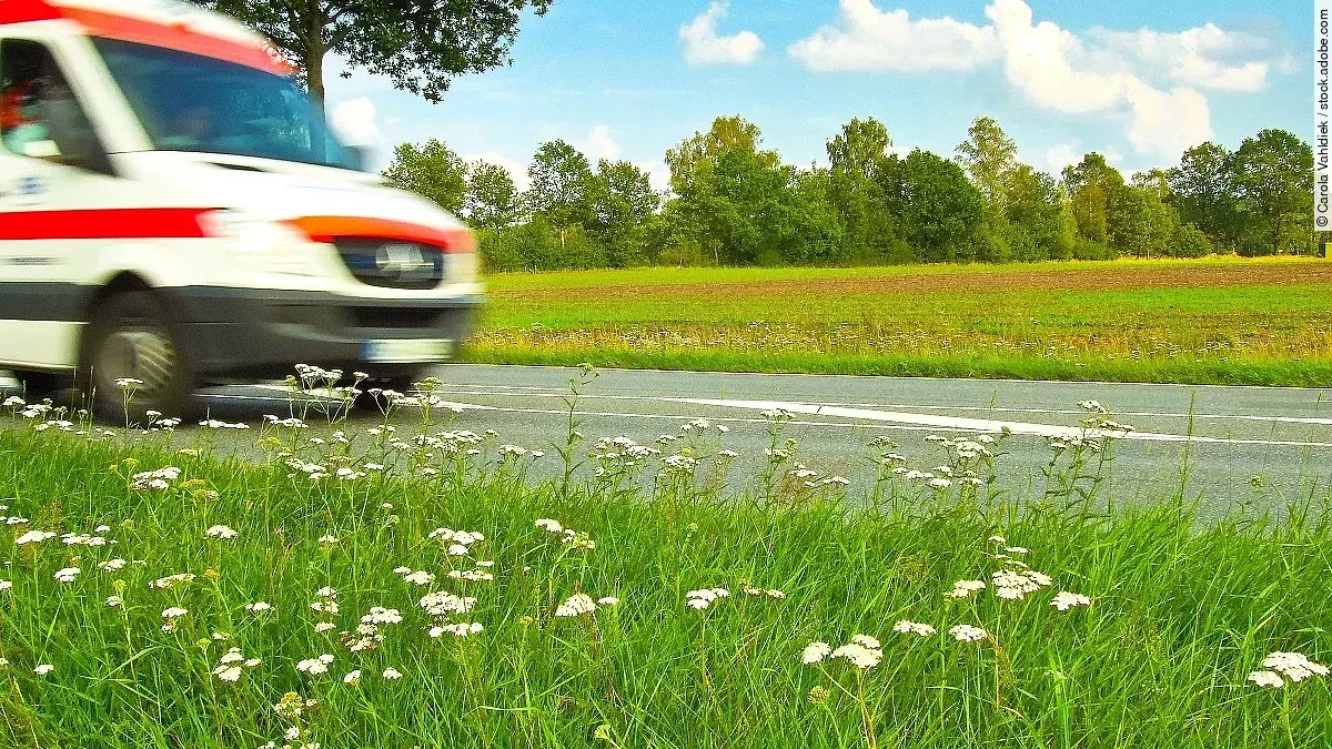 Ein Krankenwagen fährt schnell über eine Landstraße.