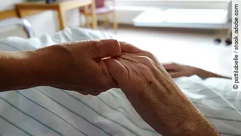 Pflege Zwei Hände, die sich auf einem weißen Bettlaken halten
