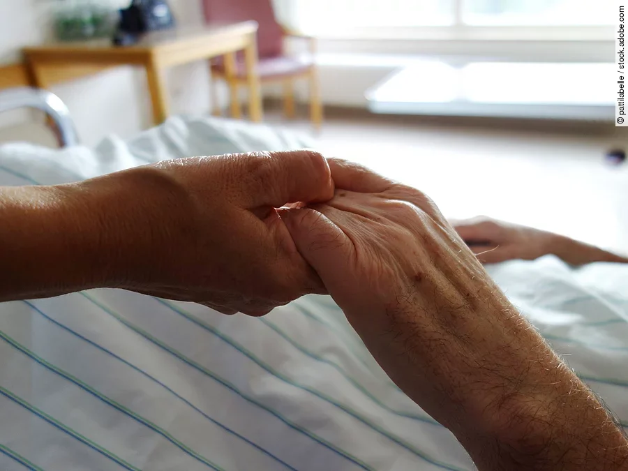 Zwei Hände, die sich auf einem weißen Bettlaken halten